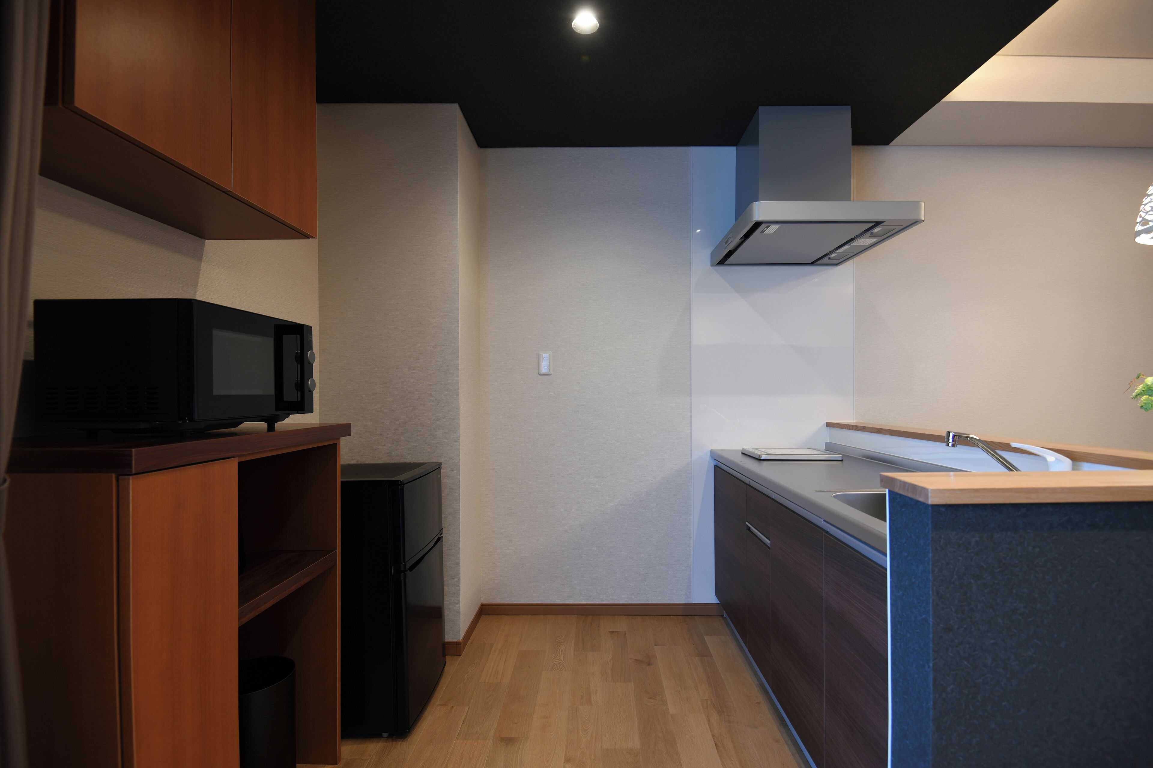 A compact kitchen with wooden cabinets, a microwave, and a modern sink.