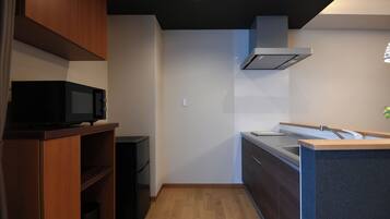 A compact kitchen with wooden cabinets, a microwave, and a modern sink.