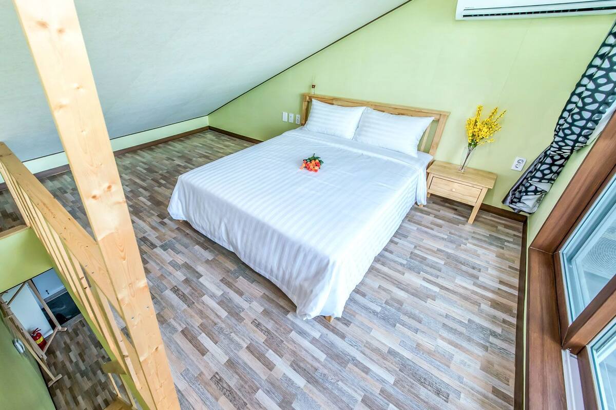 Une chambre à coucher avec un cadre de lit en bois, une couvre-lit blanche et un plancher en bois.