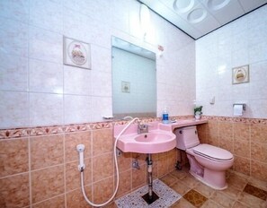A bathroom with a pink sink, toilet, and shower.