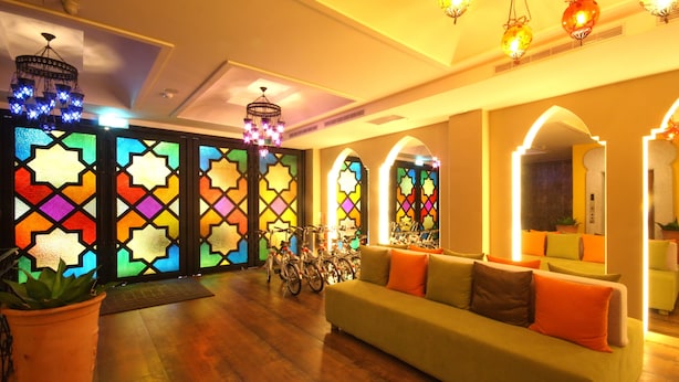A cozy interior with a sofa, colorful stained glass windows, and bicycles. - Moroccan Holiday Suite (Hualien City)