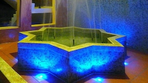 A fountain with a star-shaped basin and blue lighting, surrounded by tiled walls and arches. - Moroccan Holiday Suite (Hualien City)