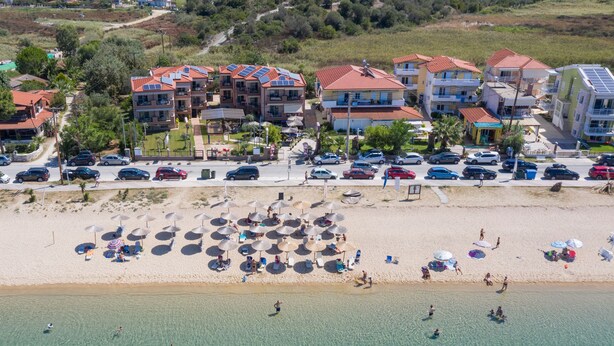 A coastal resort with multiple buildings, a sandy beach, and a clear view of the sea. - Castro Deluxe (Sithonia)