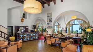 A spacious lobby with high arched ceilings, a central bar area, and comfortable seating. - Elafos Hotel (Rhodes)