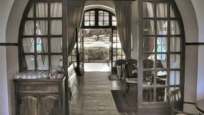 An arched doorway leading to a dining area with a view of a garden. - Elafos Hotel (Rhodes)