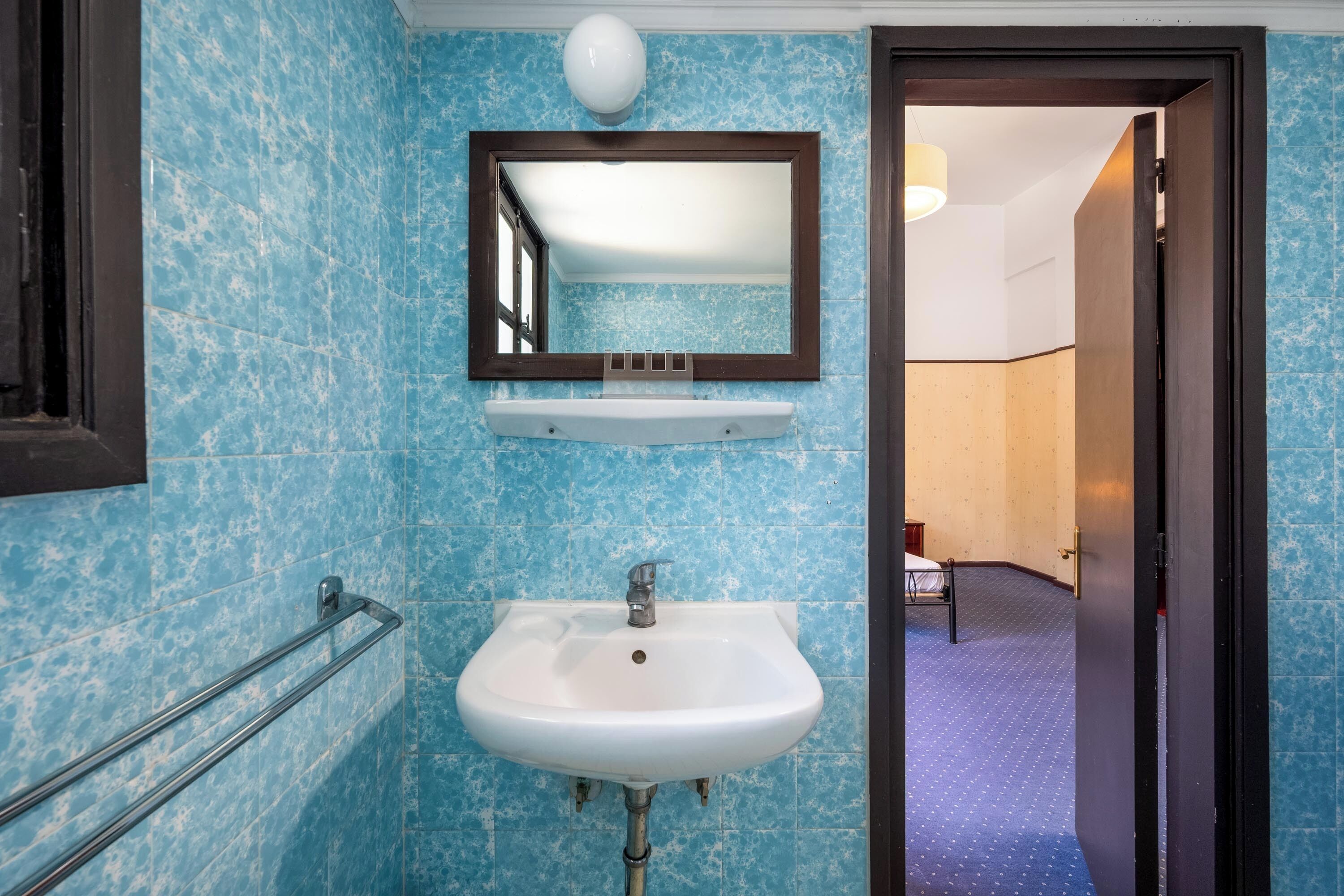 A bathroom with a white sink, a mirror, and a towel rack.