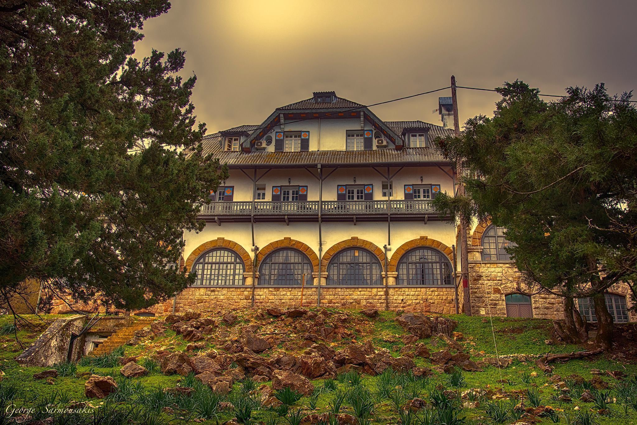 A historic building with a stone facade, multiple arched windows, and a balcony.