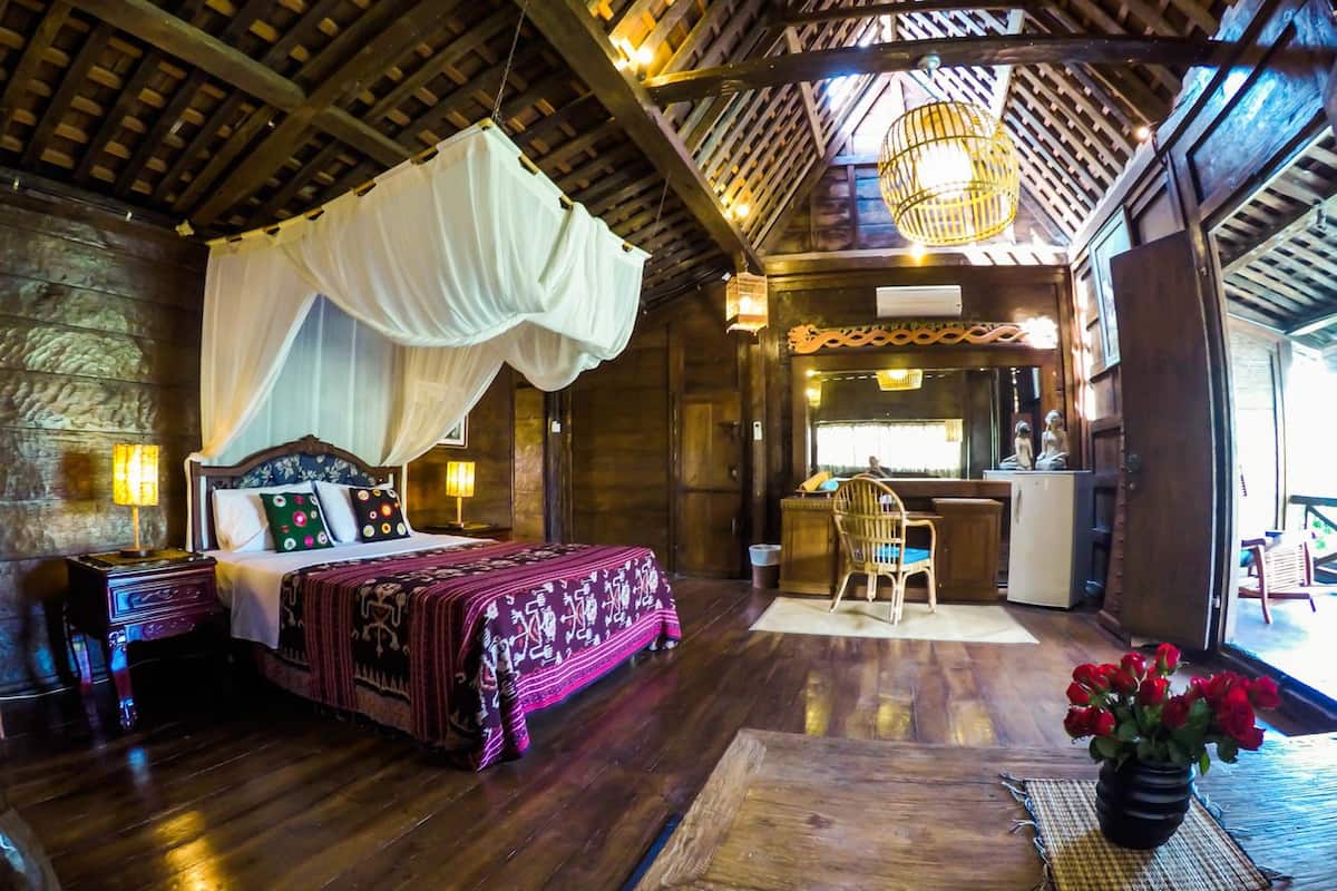 A traditional wooden room with a bed, bedside table, and a dining area with a table and chairs.