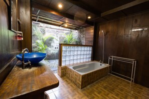 A bathroom with a wooden vanity, a blue sink, a bathtub, and a shower. - Easy Surf Dacha (Pererenan)