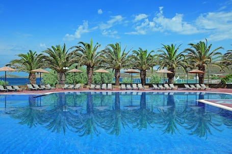 Una piscina al aire libre, sombrillas, sillones reclinables de piscina