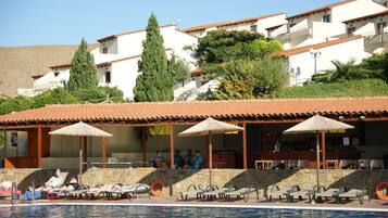 Relax by the pool with lounge chairs and umbrellas at this resort, surrounded by traditional architecture.