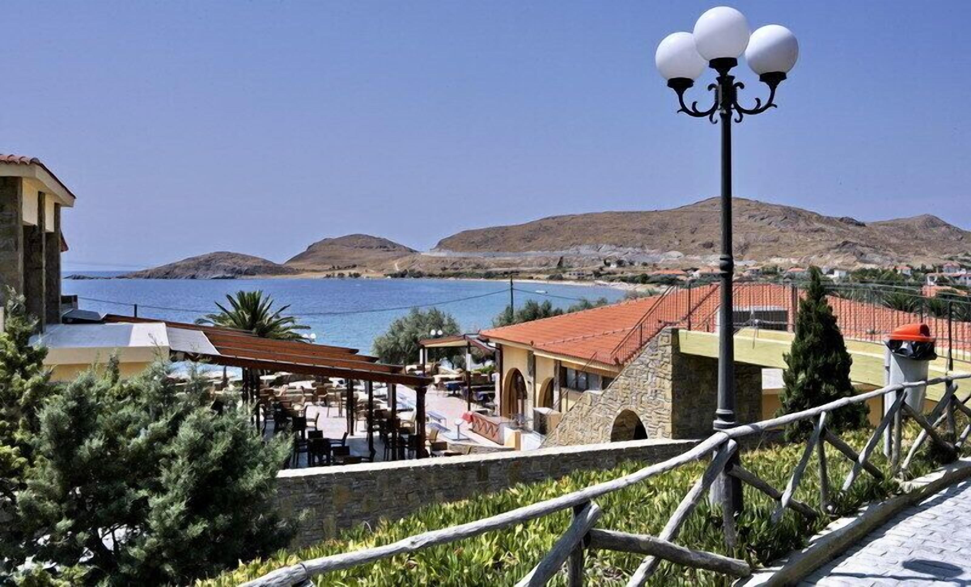 Vista costera con un edificio de piedra, una pérgola de madera y una farola.