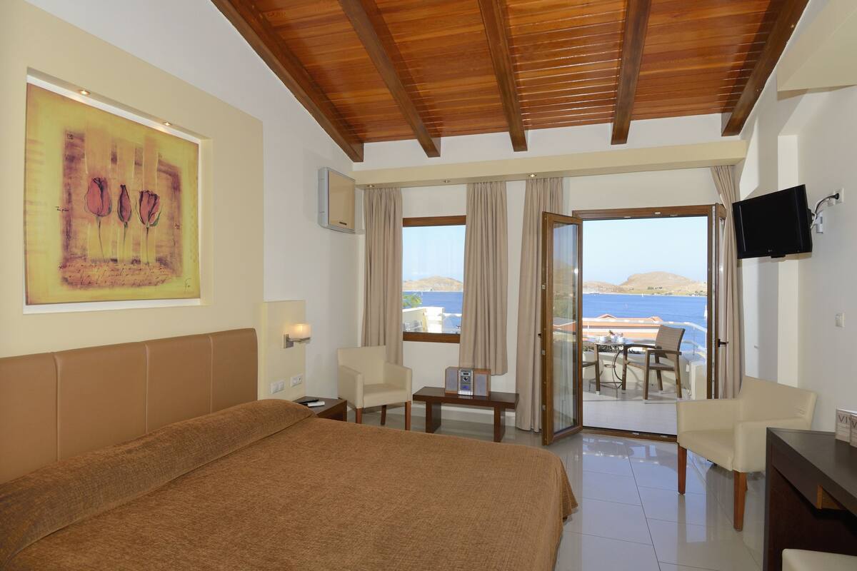 A hotel room with a bed, a desk, a chair, a TV, and a painting.