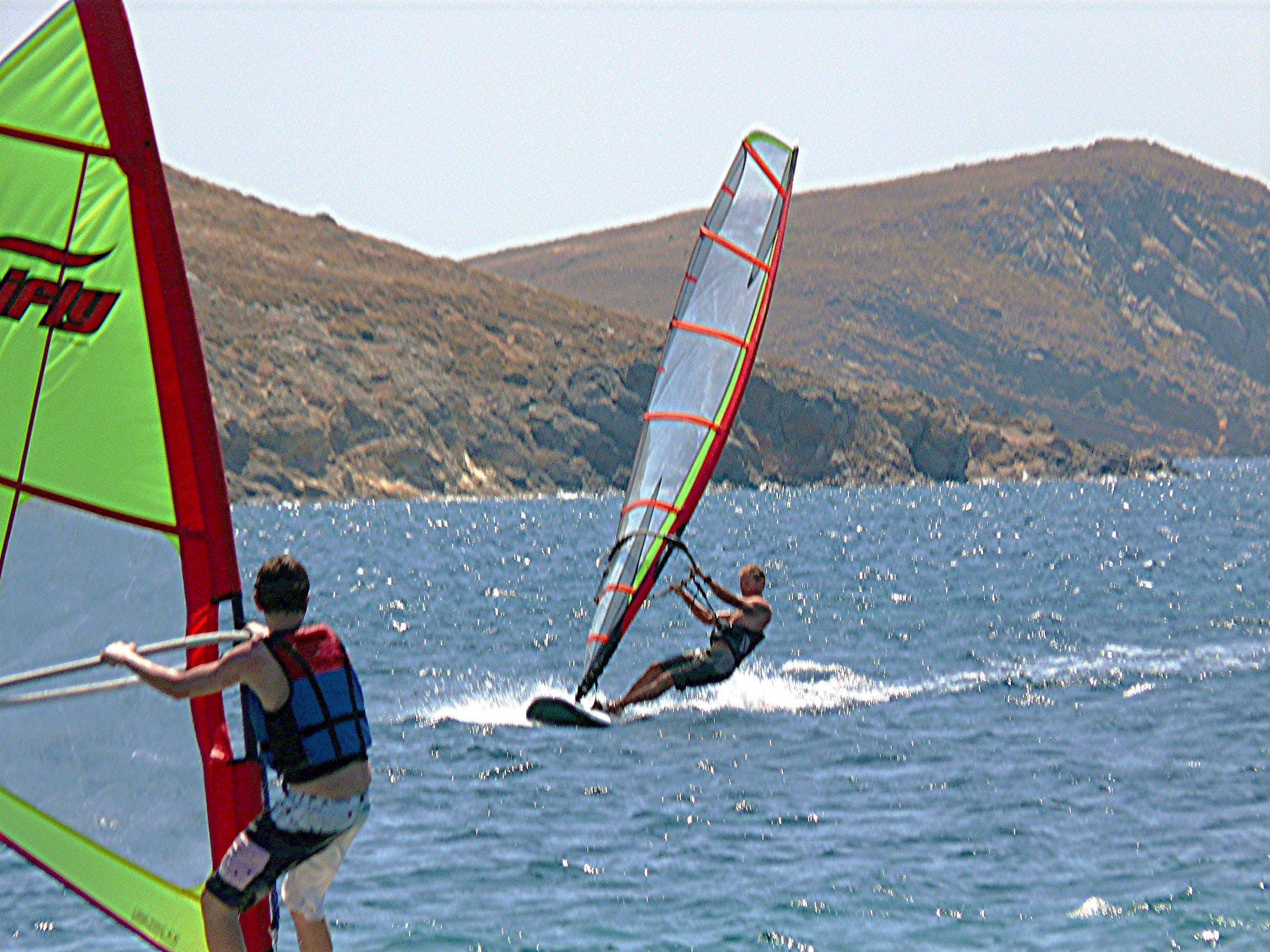 A person windsurfing on a body of water with hills in the background.