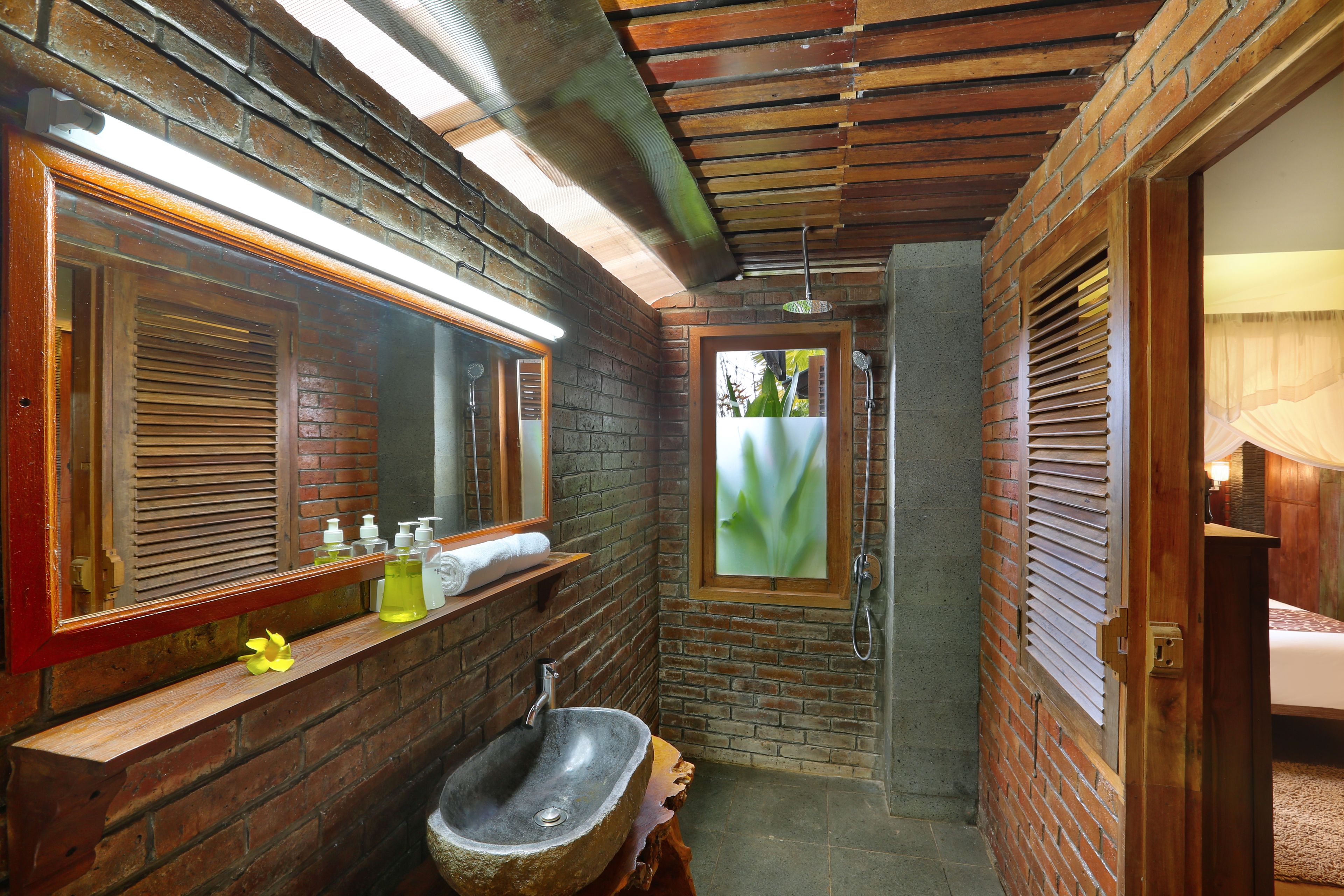 A bathroom with a stone sink, wooden vanity, and a large mirror.