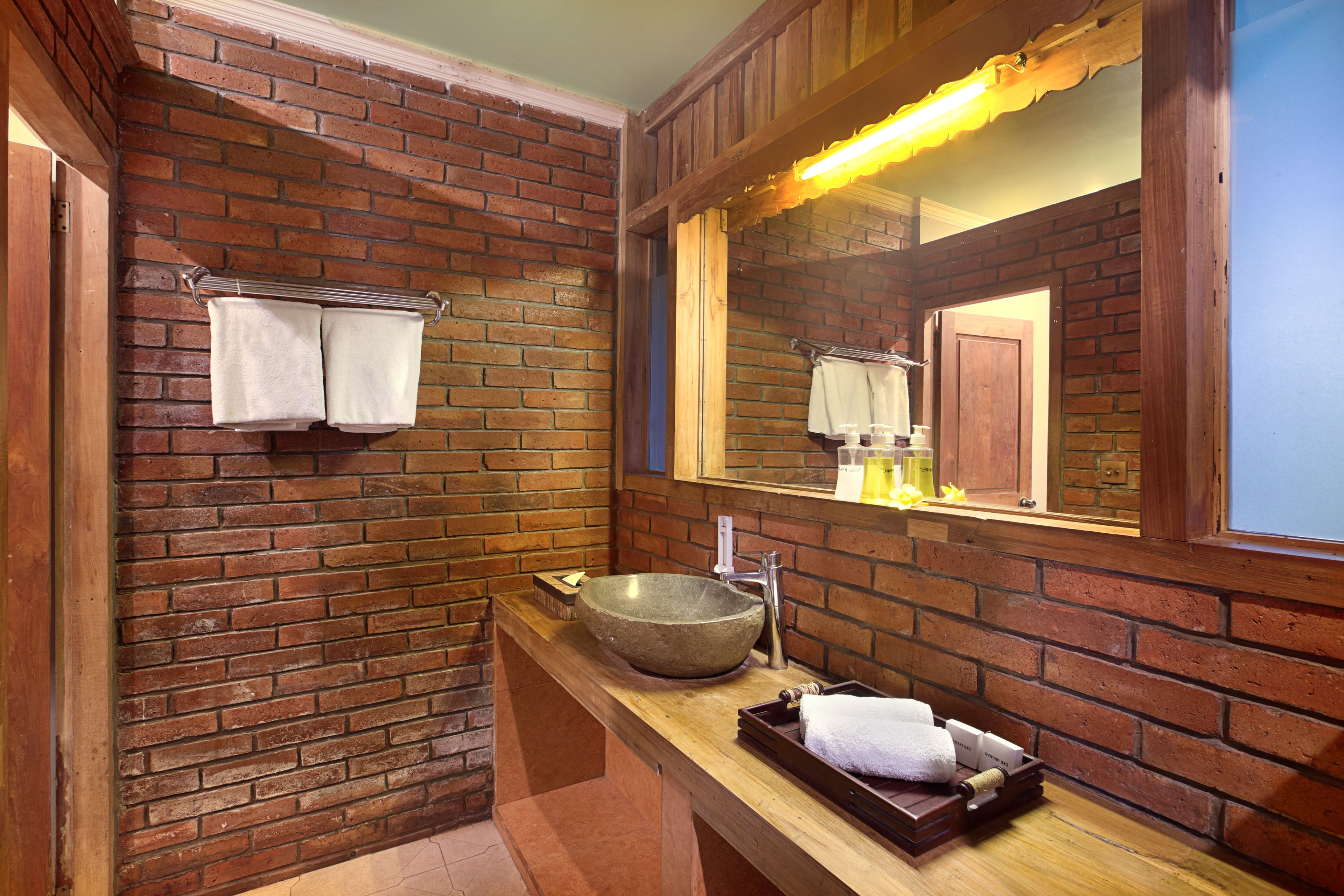 A bathroom with a stone sink, wooden vanity, and a mirror with a wooden frame.
