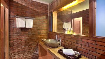 A bathroom with a stone sink, wooden vanity, and a mirror with a wooden frame.