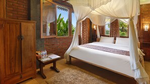 A bedroom with a large bed, wooden wardrobe, and a small table with a water bottle. - Ti Amo Bali (Penebel)