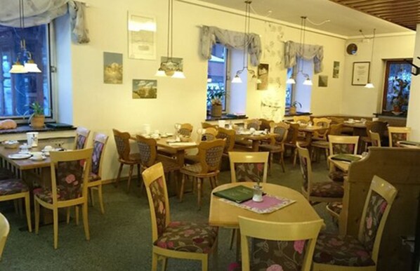 A restaurant with multiple dining tables and chairs, some with floral upholstery.