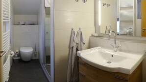 A modern bathroom with a white sink, a mirror, and a shower area. - Gästehaus Café Heck (Titisee-Neustadt)