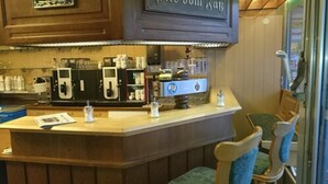 A bar area with a counter, stools, and a coffee machine. - Gästehaus Café Heck (Titisee-Neustadt)
