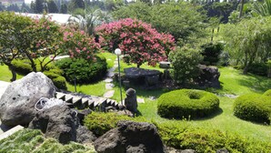 A garden with a stone table, a statue, and various shrubs. - Palace in the Forest Pension (Seogwipo)