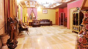 A spacious living area with a wooden ceiling, a sofa set, a decorative vase, and a wooden cabinet. - Palace in the Forest Pension (Seogwipo)