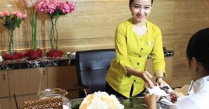 A reception area with a receptionist, a desk with a computer, and a vase with flowers. - Horison Hotel Sukabumi (Sukabumi)