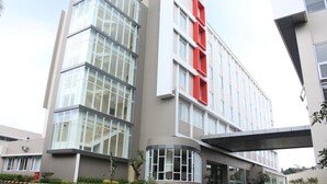 Un bâtiment moderne doté d’une grande enseigne verticale rouge bien visible, de grandes fenêtres et d’un espace d’entrée abrité.