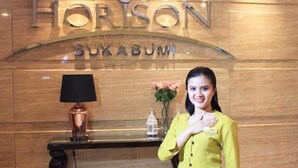 Un comptoir d’accueil avec une plaque nominative indiquant « HORIZON SUKABUMI » et une lampe.