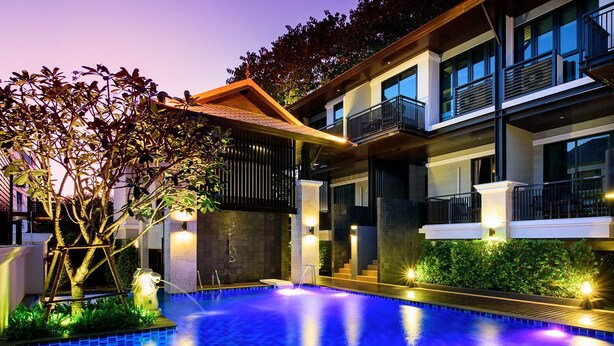 A modern hotel with a swimming pool, outdoor lighting, and a multi-story building with balconies. - Yotaka Bangkok Hotel (Bangkok)