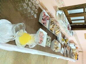 A breakfast buffet with various food items and a pitcher of orange juice.