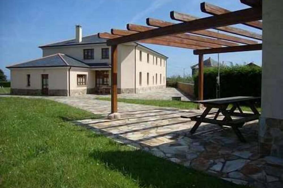 A house with a stone patio, a wooden pergola, and a picnic table.