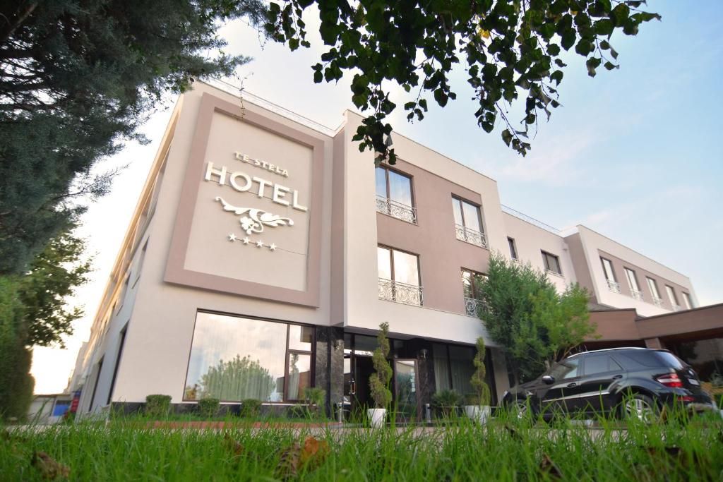 A hotel with a modern facade, large windows, and a car parked in front.