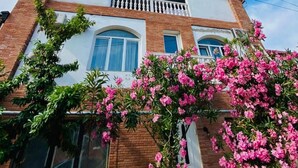 A two-story building with a white facade and a brick base, featuring a balcony on the upper floor. - Hotel Isaka (Tbilisi)