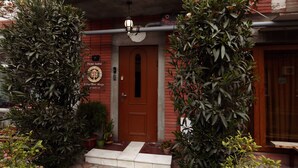 A hotel entrance with a brown door, a signboard with the hotel name, and potted plants around. - Hotel Isaka (Tbilisi)