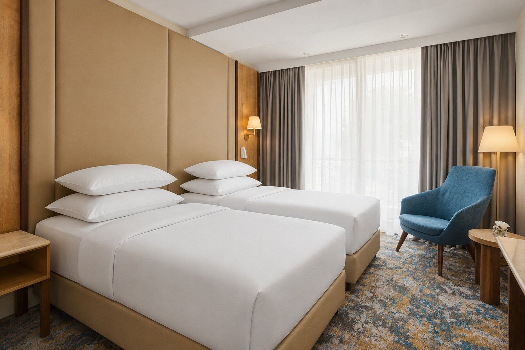 A hotel room with two beds, a desk, a chair, and a window with curtains.