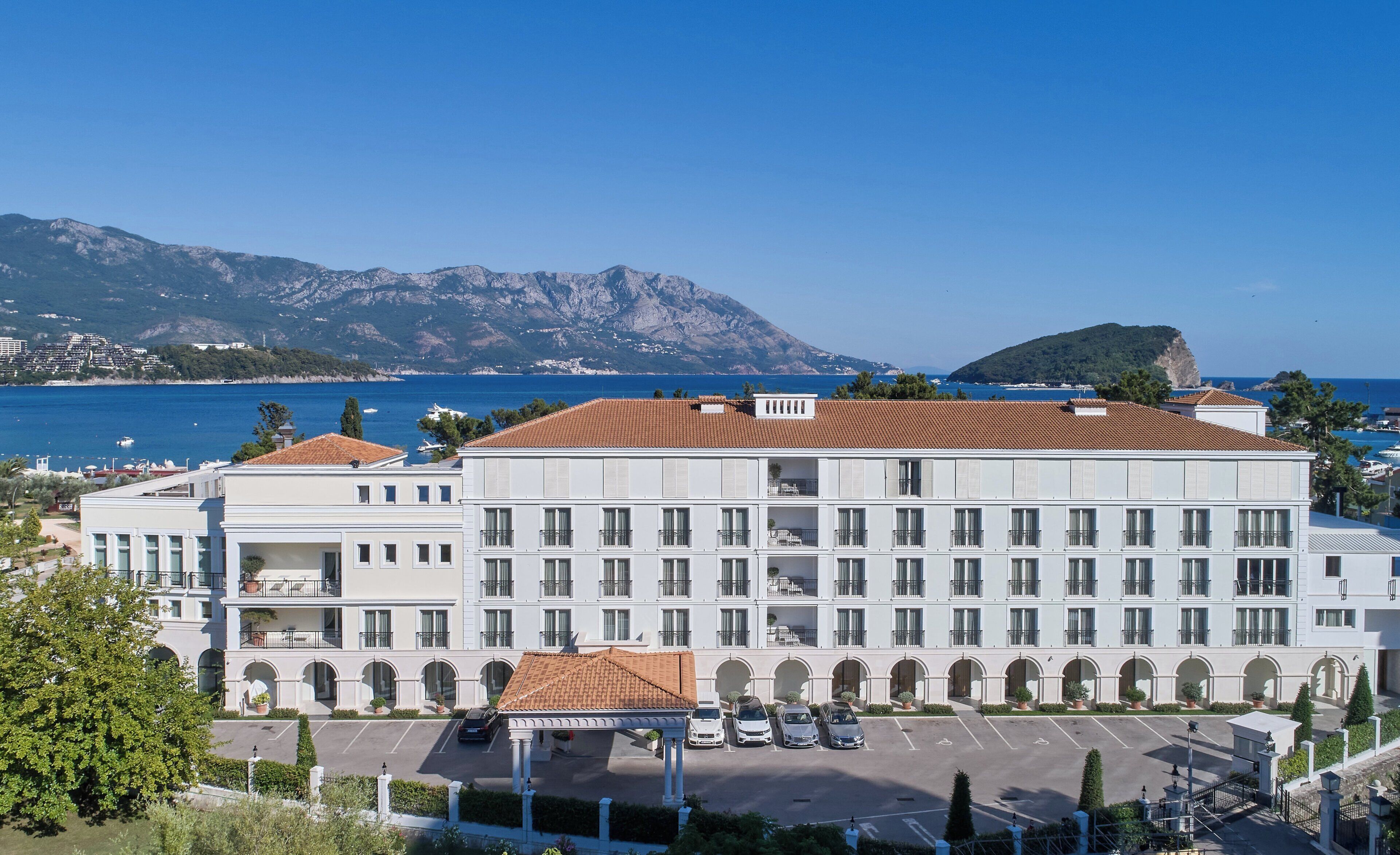 Un hotel con un patio central, varios balcones y vistas al mar y a las montañas.