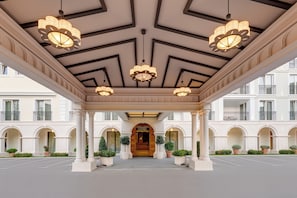 Entrada de hotel con un porche cubierto, columnas y candelabros.