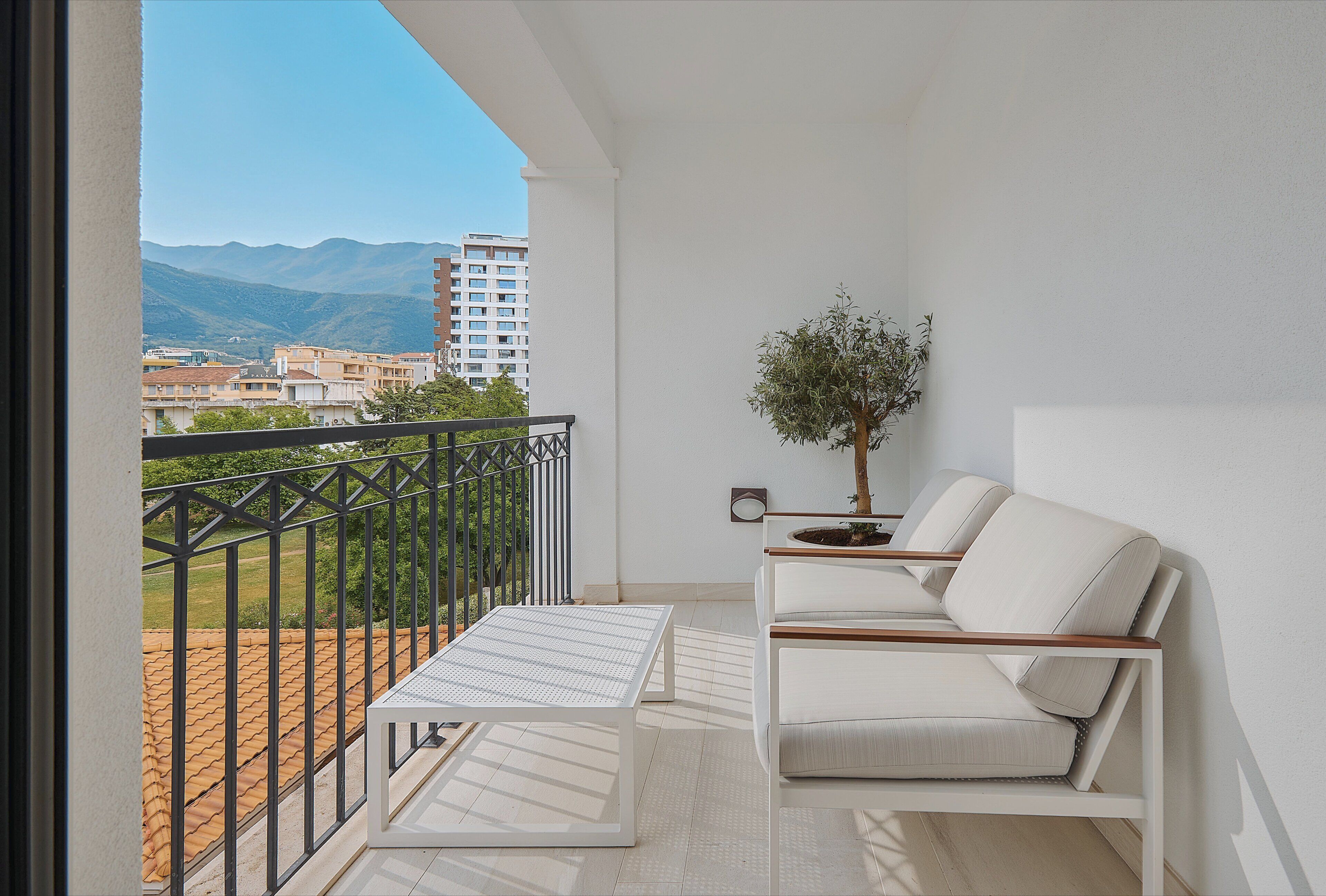 Un balcon avec un canapé blanc, une petite table et une plante en pot.