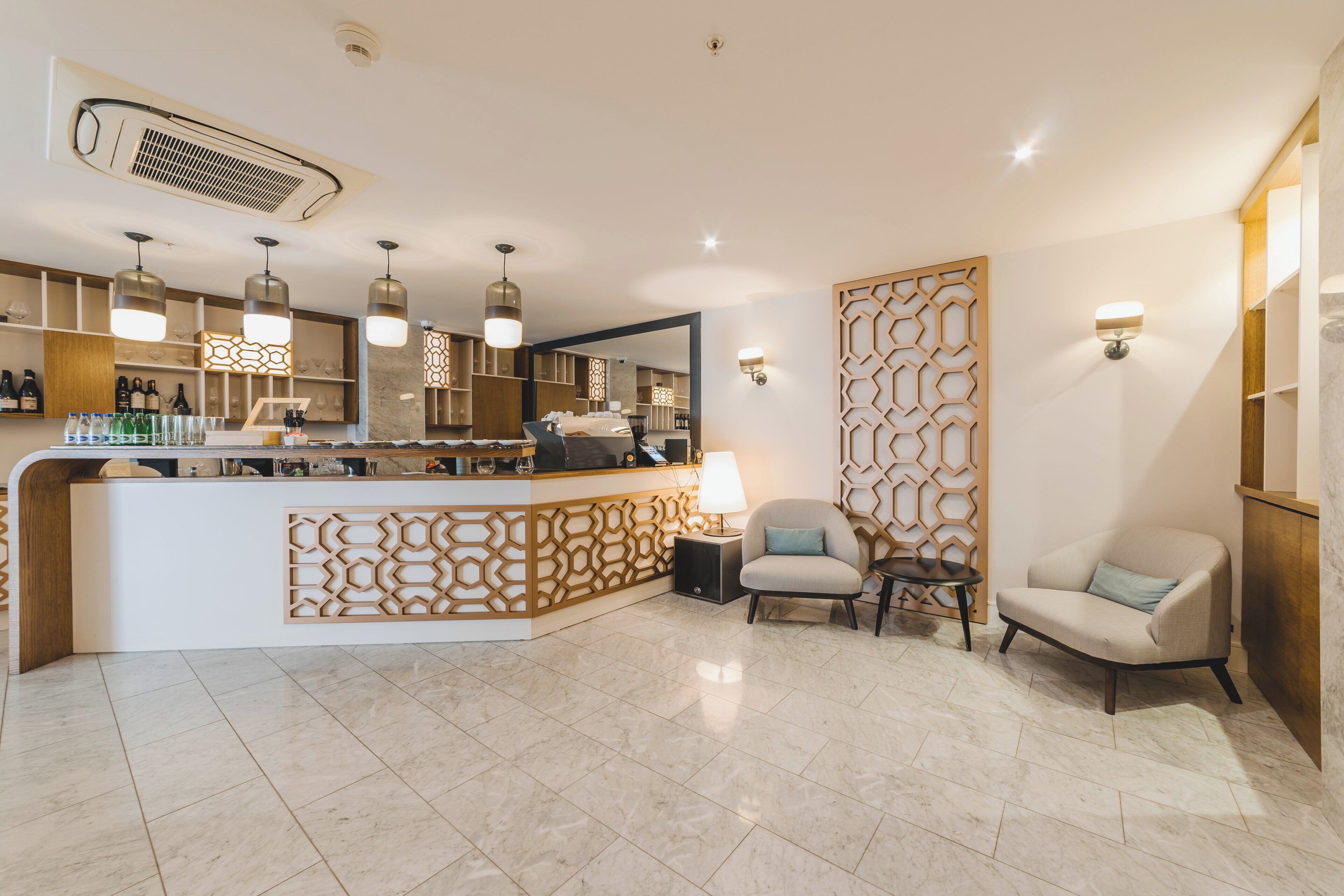 A modern hotel lobby with a reception desk, seating area, and a decorative wall.
