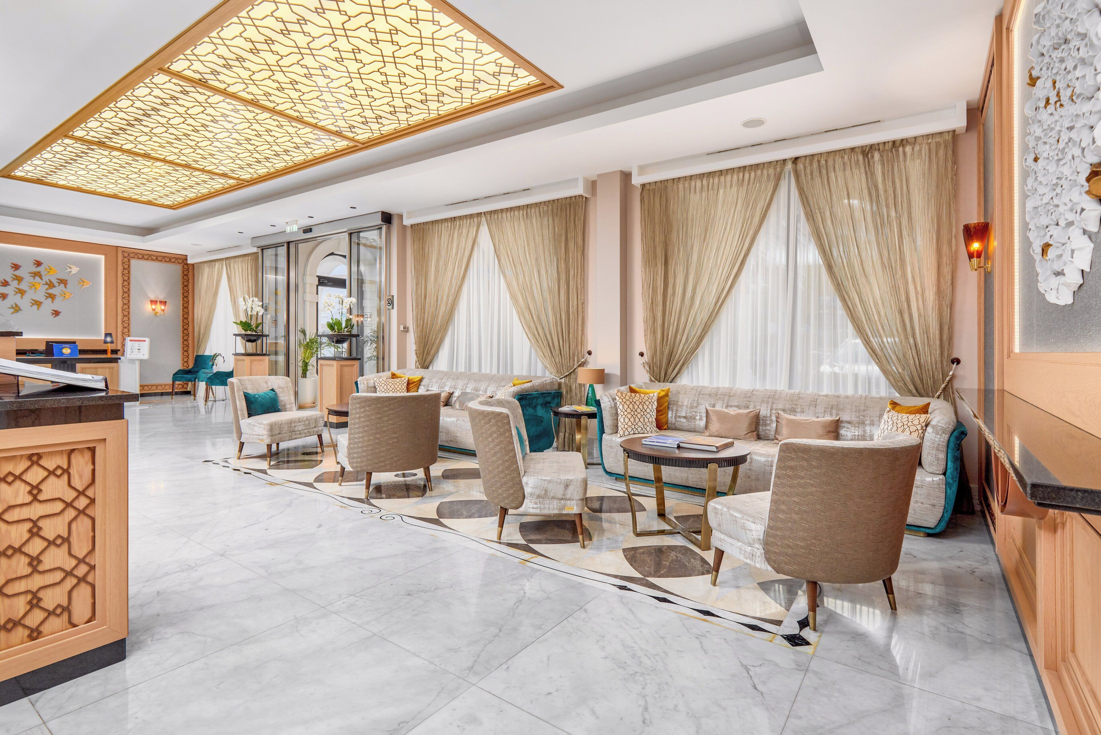 A spacious lobby with a reception desk, seating area, and large windows with curtains.