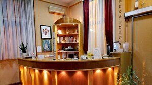 A reception desk with a wooden finish, a built-in bookshelf, and a potted plant. - Hotel Slodes (Belgrade)