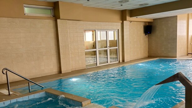 An indoor swimming pool with clear water, a diving board, and a ceiling with ventilation. - Hotel Slodes (Belgrade)