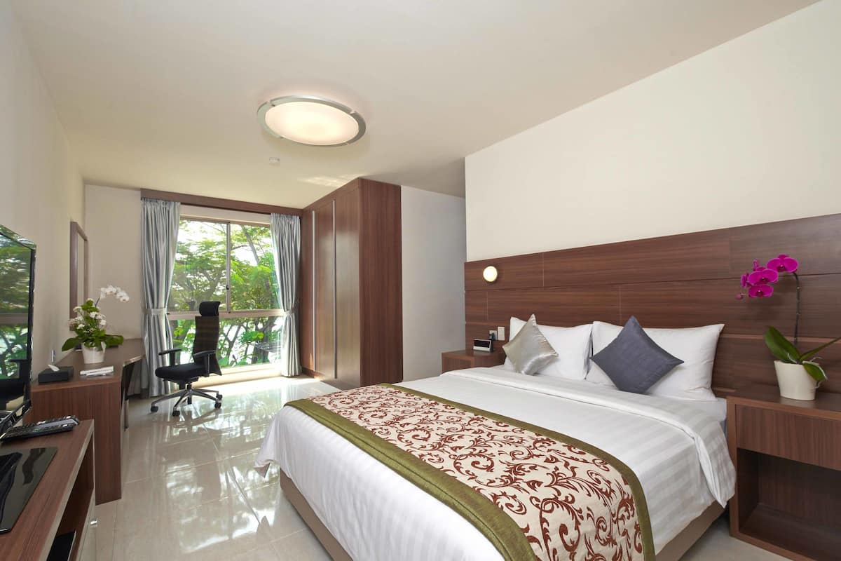 Een hotelkamer met een groot bed, een bureau met een computer, een stoel en een televisie.