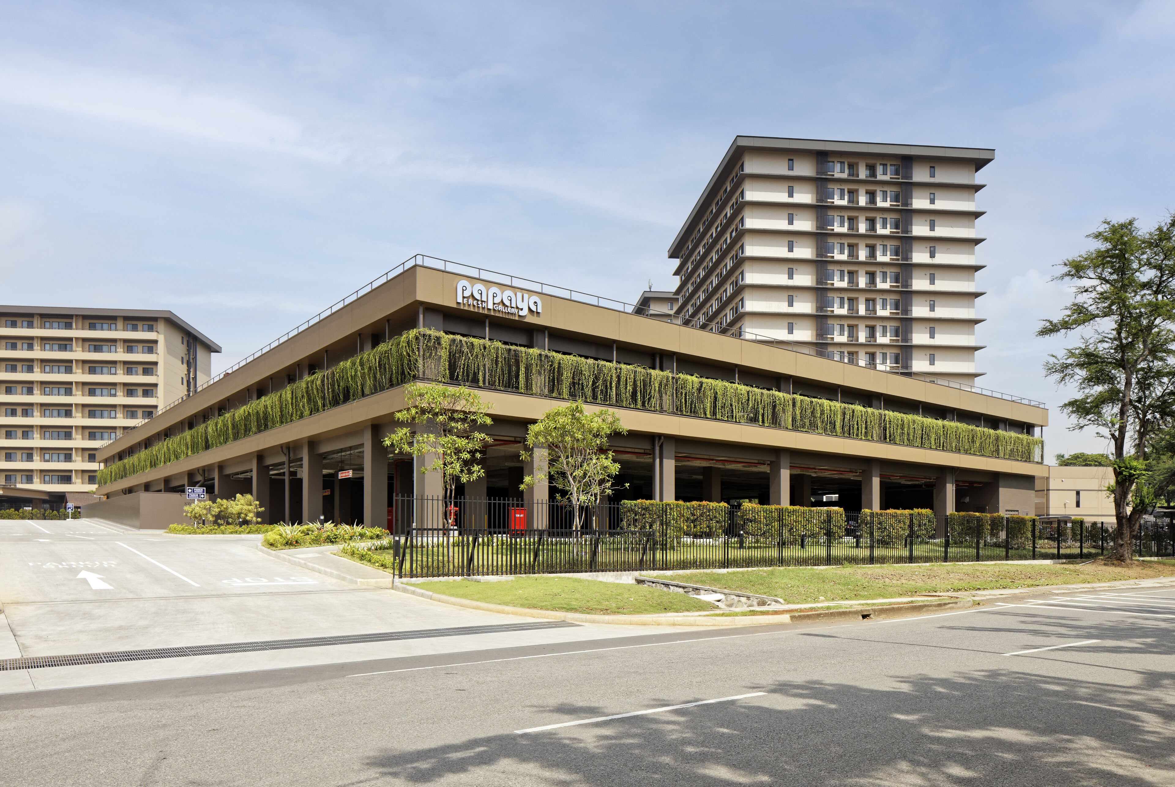 Un hotel moderno con techo plano, zona de estacionamiento techada y un letrero que dice 'Papaya'.