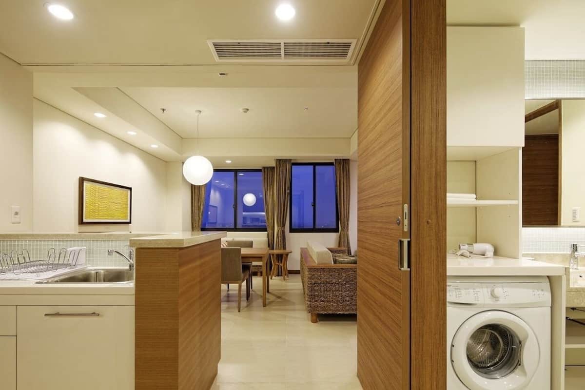 Een moderne keuken met een ingebouwde wasmachine, een eethoek met een bank, en uitzicht op de stad 's nachts.