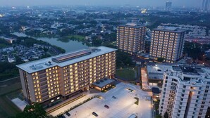 A high-rise hotel with multiple floors, a parking lot, and a river in the background.