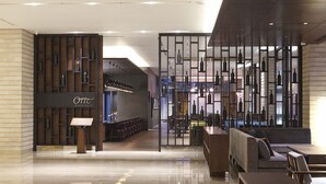 A modern hotel lobby with a bar area, seating, and a wine display.
