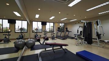 A gym with exercise equipment, large windows, and a view of the outdoors.